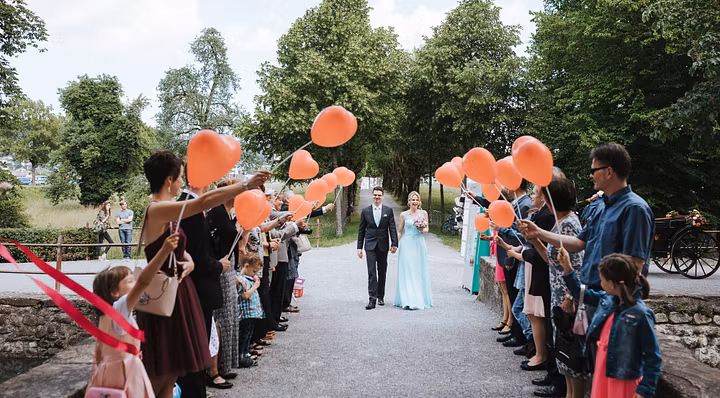 Ein Hochzeitspaar schreitet durch eine Festgesellschaft, die vor Schloss Hallwyl Spalier steht.