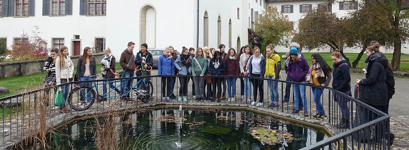 Eine Gruppe Jugendliche steht um einen grossen Brunnen vor dem Kloster Wettingen