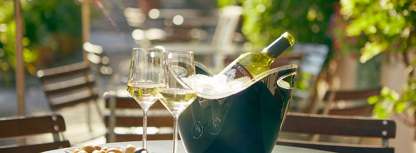 Wein und Weingläser auf einem Tisch auf der Terrasse im Bistro Schloss Wildegg