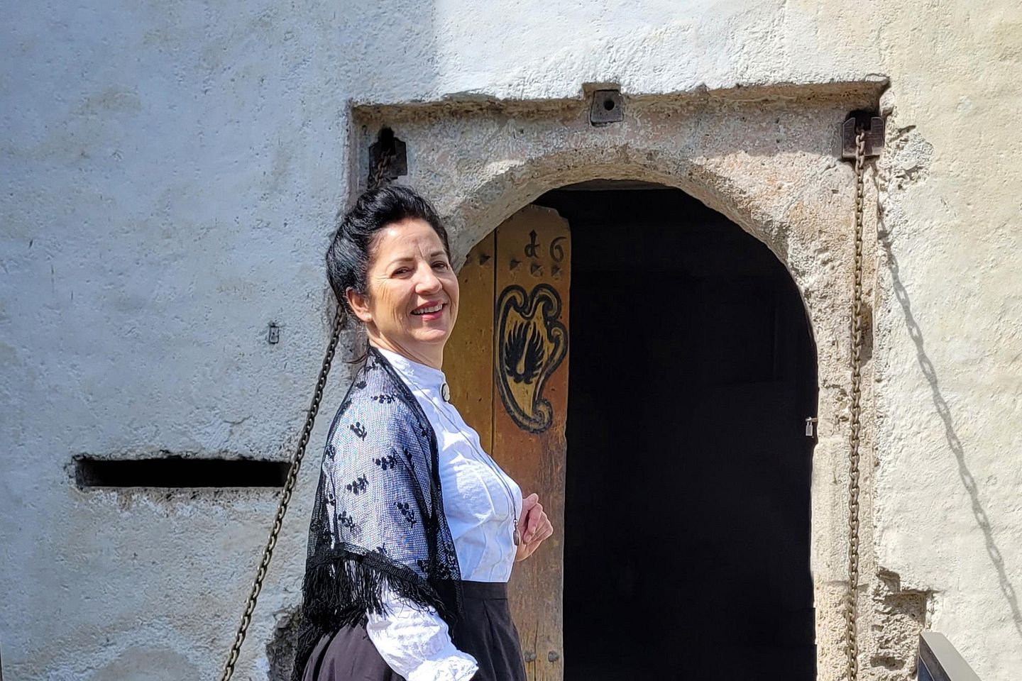 Eine Frau im Kostüm (Rolle: Wilhelmina von Hallwyl) steht vor einem grossen Steintor von Schloss Hallwyl