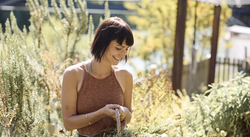 Eine Frau mit Korb steht inmitten von Pflanzen.