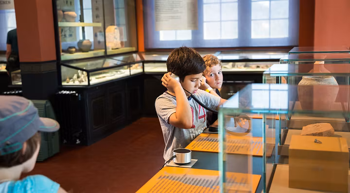 Zwei Jungen betrachten mit Kopfhörern die Dauerausstellung im Vinodnissa Museum