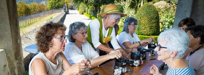 Workshop im Garten: Eine Gruppe Frauen setzt am Tisch und kocht Salbe; im Hintergrund der Garten von Schloss Wildegg