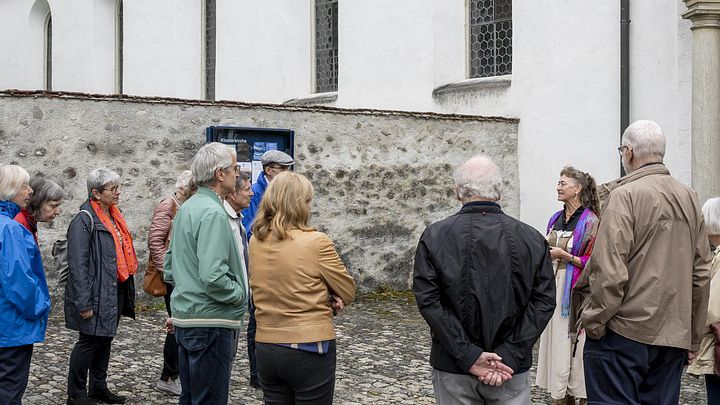 Eine Gruppe Besucherinnen und Besucher mit Museumsführerin vor dem Kloster Wettingen