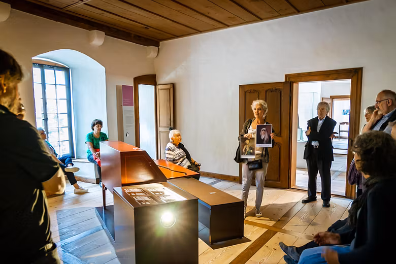 Eine Museumsführerin steht mit einer Gästegruppe in einem Museumsraum von Schloss Hallwyl.