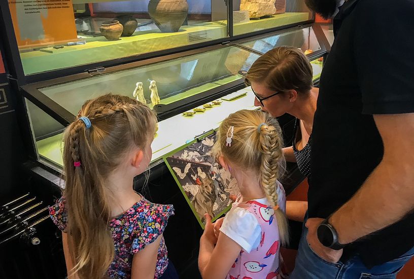 Eine Familie steht mit einem Plan vor einer Vitrine im Vindonissa Museum.
