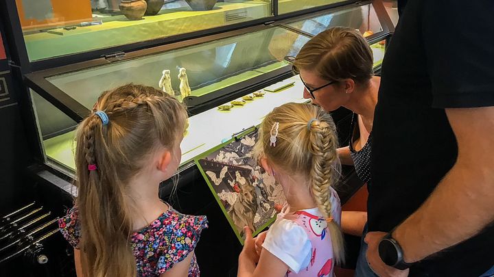 Eine Familie steht mit einem Plan vor einer Vitrine im Vindonissa Museum.