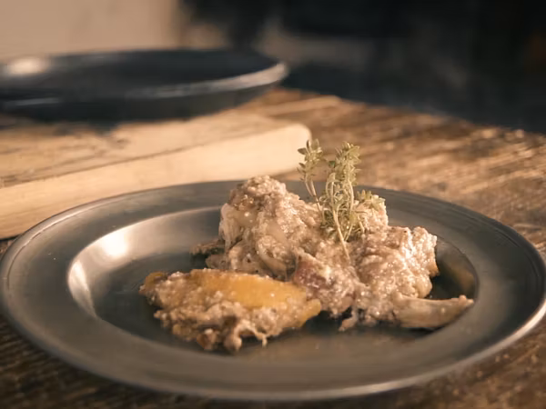 Eine Portion Huhn an Zitrone auf einem Teller, der auf einem Tisch in der Mittelalterküche von Schloss Lenzburg steht.