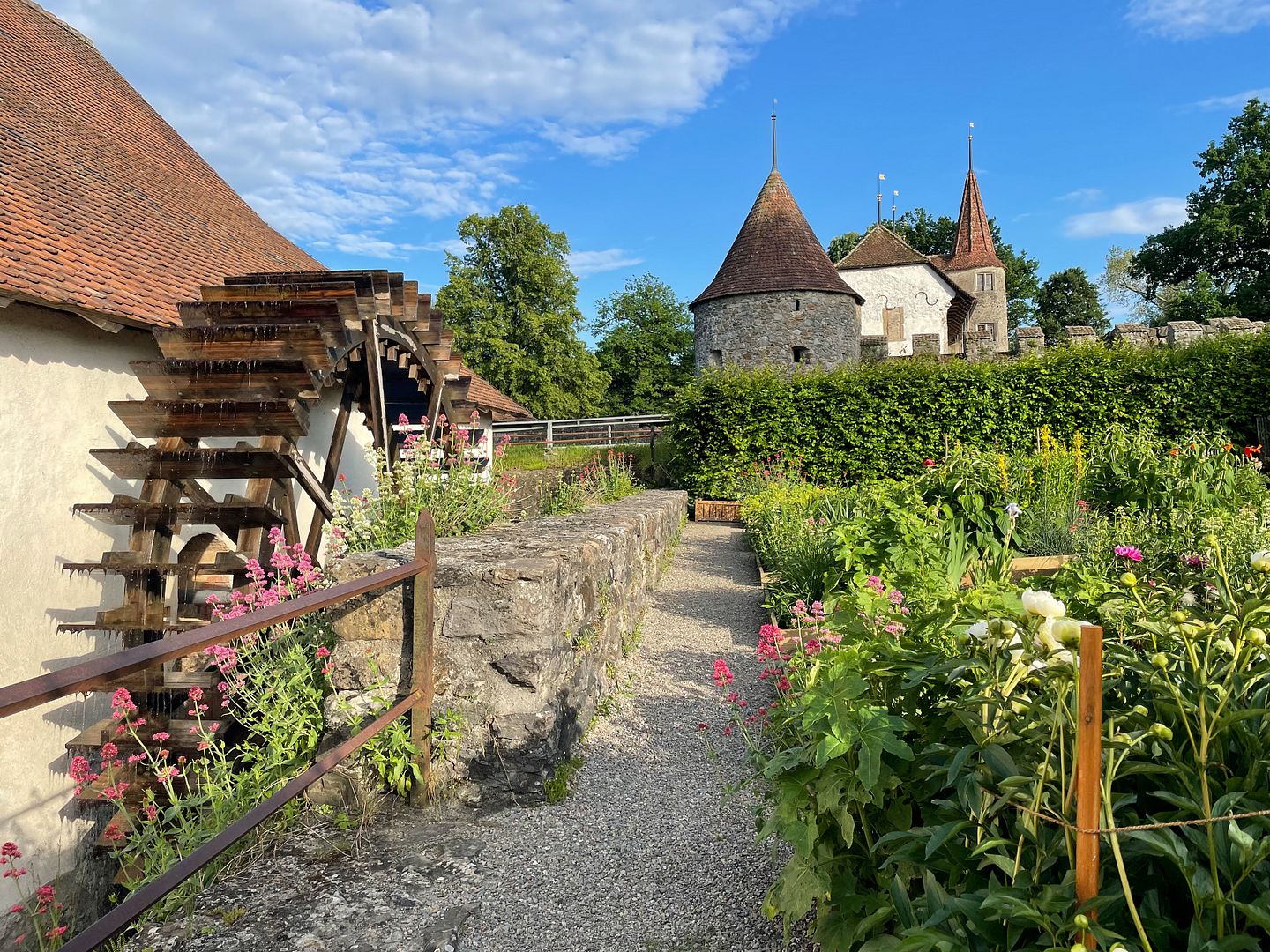 Aussenansicht Mühle Schloss Hallwyl mit Mühlenrad (links), Garten (rechts) sowie Schloss Hallwyl (im Hintergrund)