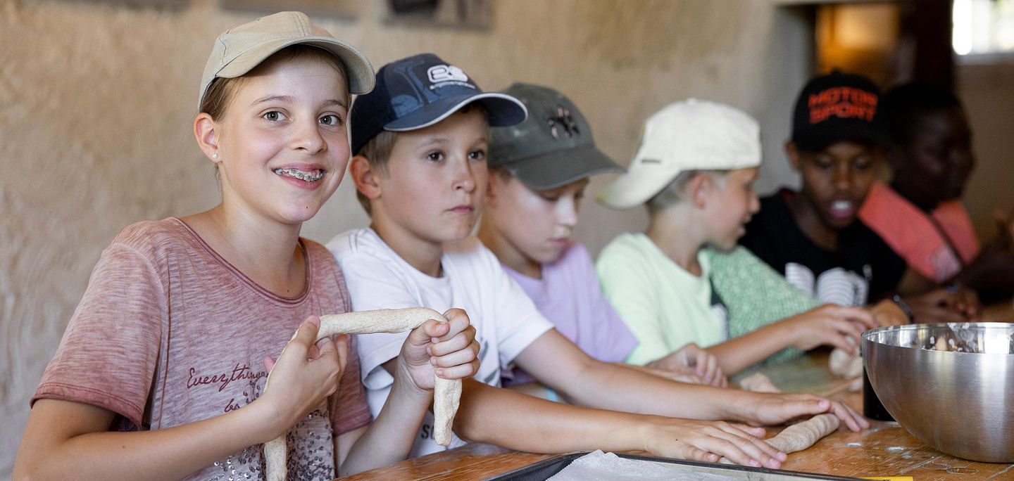 Kinder am Tisch sitzend, die Teig für Brot formen im Schloss Hallwyl