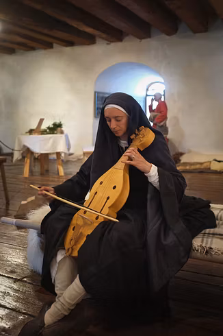 Eine mittelalterlich gekleidete Musikerin spielt auf ihrem Instrument im Rittersaal von Schloss Lenzburg.