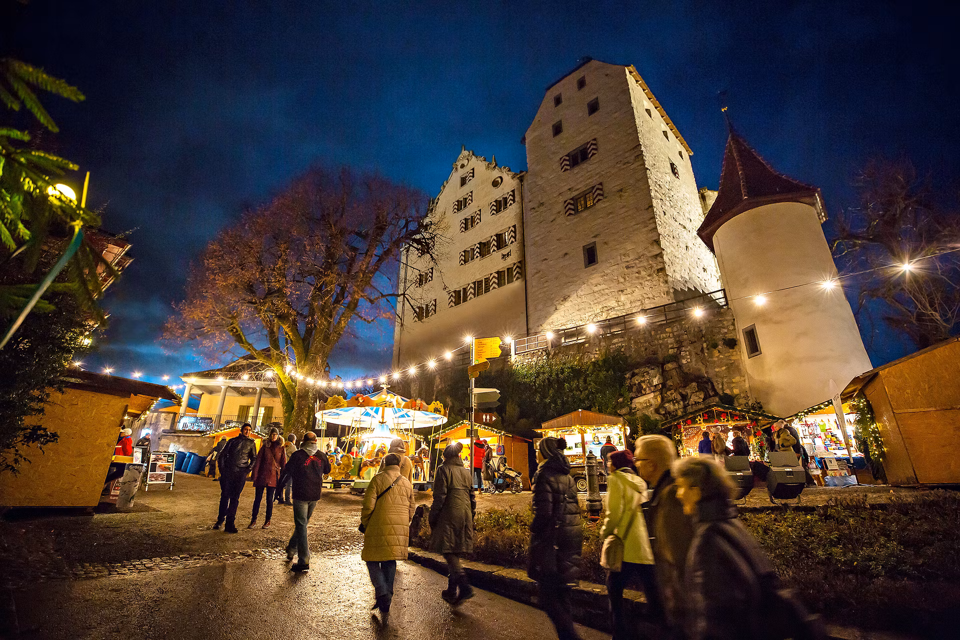 Nachtaufnahme von Schloss Wildegg mit stimmungsvoll beleuchtetem Weihnachtsmarkt.