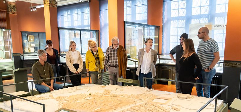 Führung im Vindonissa Museum. Eine Besuchergruppe steht mit einer Geschichtsvermittlerin um das Lagermodell des Legionslagers Vindonissa