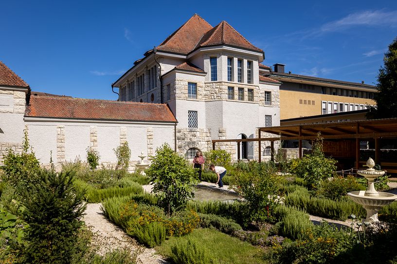 Römischer Garten Vindonissa Museum: Übersicht des Gartens mit geometrisch angelegten Wegen und Gartenbeeten. Im Hintergrund das Museumsgebäude vom Vindonissa Museum.