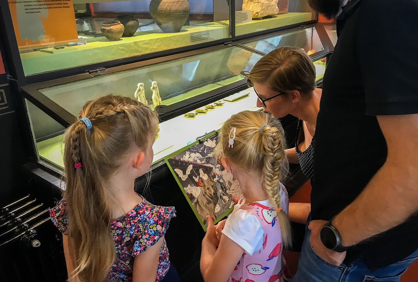 Eine Familie steht mit einem Plan vor einer Vitrine im Vindonissa Museum.