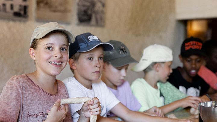 Kinder am Tisch sitzend, die Teig für Brot formen im Schloss Hallwyl