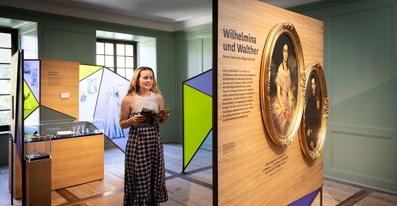Eine Frau steht in einem Ausstellungraum mit bunten Wänden.