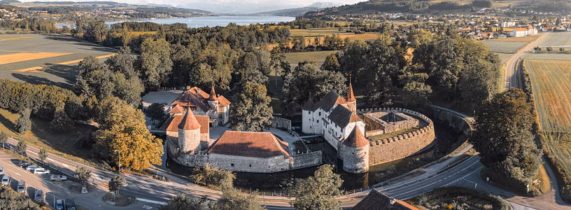 Luftaufnahme von Schloss Hallwyl mit Hallwilersee im Abendlicht