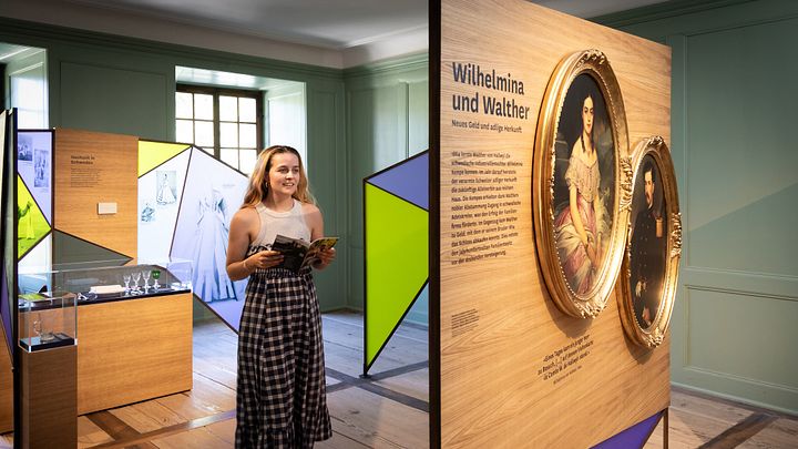 Eine Frau steht in einem Ausstellungraum mit bunten Wänden.