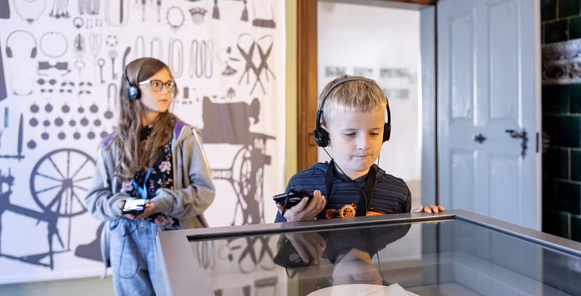 Zwei Kinder mit Kopfhörer in der Ausstellung von Schloss Hallwyl.