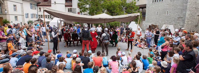Belebter Hof von Schloss Lenzburg, in der Mitte steht ein grosses Zelt mit mittelalterlich gekleideten Personen.