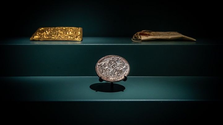 Eine Münze und weitere historische Objekte in einer Vitrine.