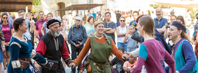Eine Gruppe Personen tanzt am Mittelaltermarkt auf Schloss Lenzburg in historischer Kleidung zu Musik