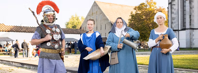 Gruppenbild mit vier historisch gekleideten Personen: Ein Römer, eine Römerin, eine mittelalterliche Nonne sowie eine Magd aus dem Mittelalter.
