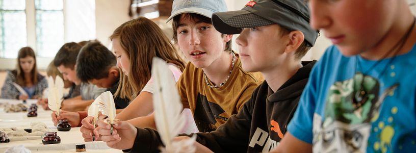 Eine Schulklasse beim Schreiben mit Tinte und Federkiel.