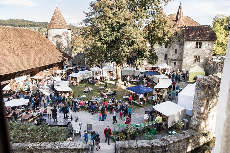 Mosttage Schloss Hallwyl: Blick von oben in den Schlosshof, der mit Marktständen und Besucherinnen und Besuchern gefüllt ist.