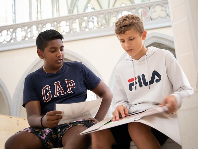 Zwei Schüler sitzen mit Unterrichtsmaterialien in der Klosterkirche Königsfelden.