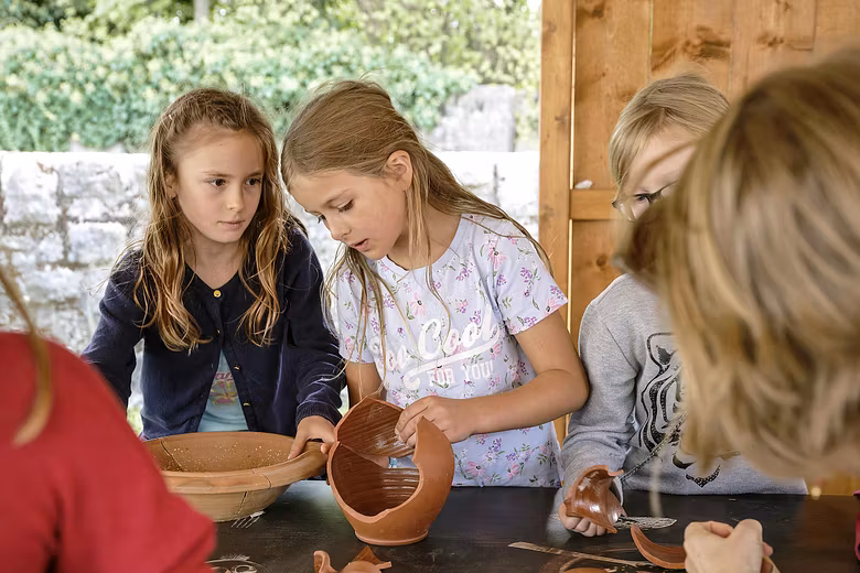 Kinder setzen im römischen Garten vom Vindonissa Museum Scherben eines Kruges zusammen.