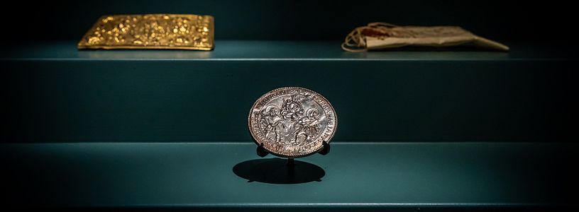 Eine Münze und weitere historische Objekte in einer Vitrine.