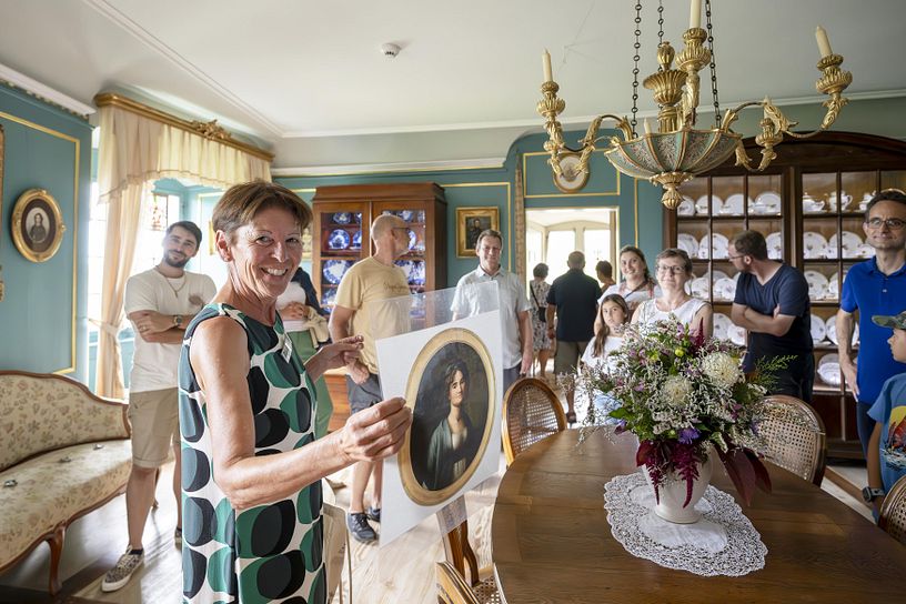 Eine Museumsführerin mit Besucherinnen und Besucher in der Ausstellung von Schloss Wildegg. Die Museumsführerin blickt lachend direkt in die Kamera.