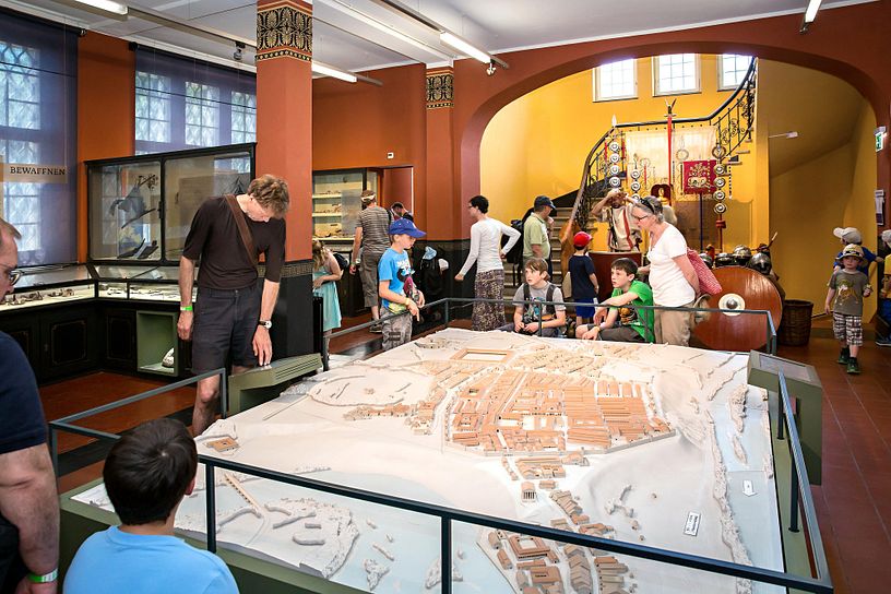 Mehrere Erwachsene und Kinder stehen vor dem grossen Modell des Römerlagers im Vindonissa-Museum.