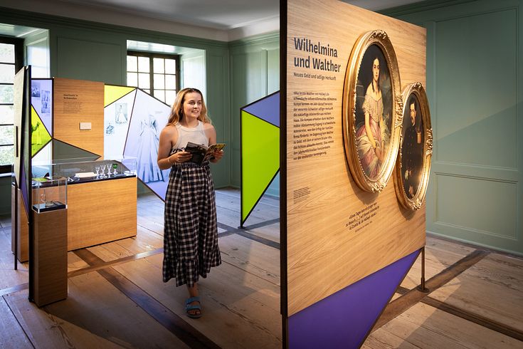 Eine Frau steht in einem Ausstellungraum mit bunten Wänden.