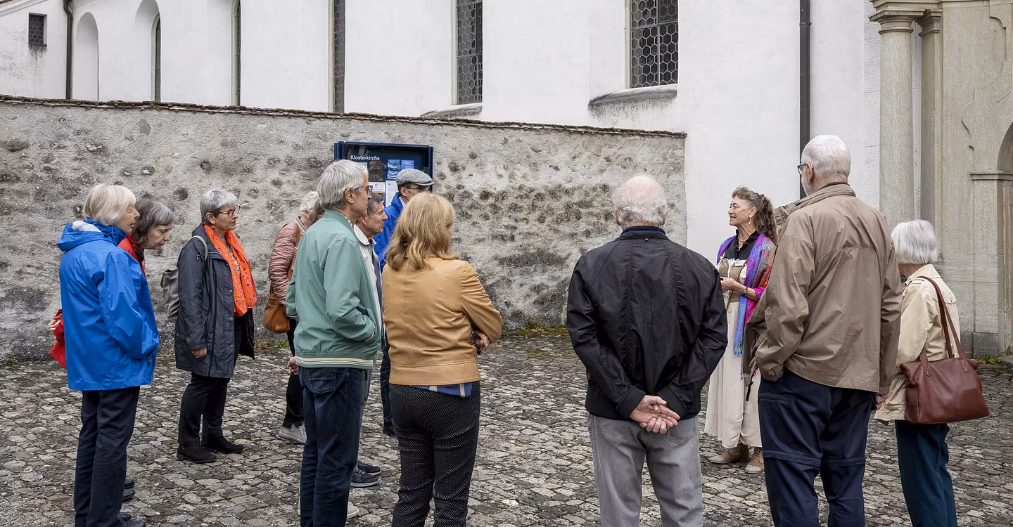 Eine Besuchergruppe und eine Museumsführerin stehen im Kreis vor dem Kloster Wettingen.