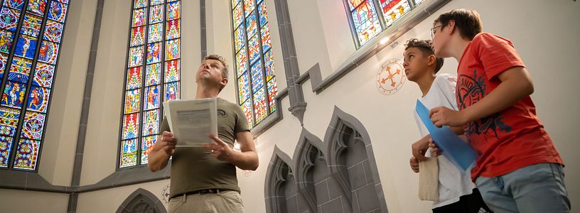 Besucher und Besucherinnen betrachten die berühmten Glasfenstern auf Kloster Königsfelden