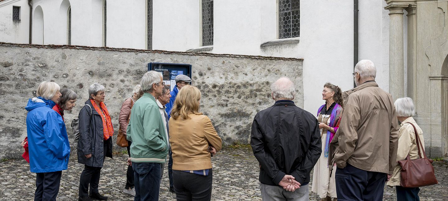 Eine Gruppe Besucherinnen und Besucher mit Museumsführerin vor dem Kloster Wettingen