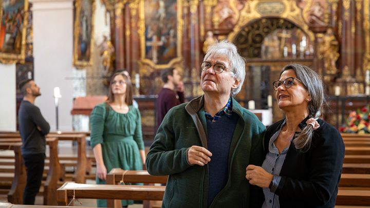 Ein Ehepaar steht in der Klosterkirche Wettingen und blickt staunend in die Höhe. Dahinter weitere Personen in Unschärfe.