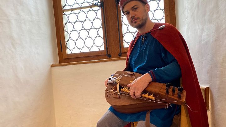Eine als mittelalterlicher Spielmann verkleidete Person mit einer Drehleiher auf Schloss Lenzburg.