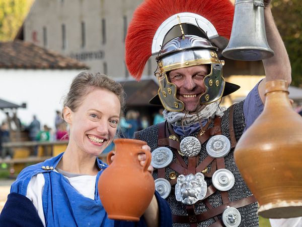 Foto von einem Mann und einer Frau in römischer Kleidung mit Karaffen im Legionärspfad Vindonissa.