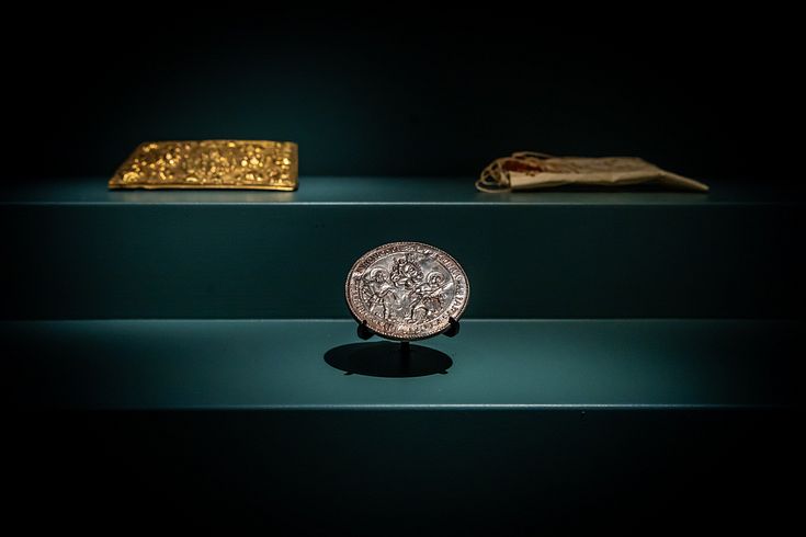 Eine Münze und weitere historische Objekte in einer Vitrine.