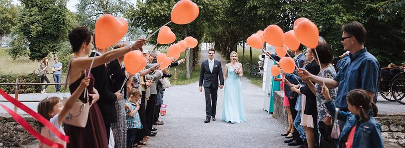 Ein Hochzeitspaar schreitet durch eine Festgesellschaft, die vor Schloss Hallwyl Spalier steht.