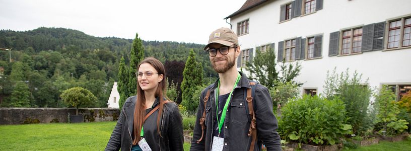 Eine Frau und ein Mann schreiten in Freizeitbekleidung durch den Garten der Klosterhalbinsel Wettingen (Foxtrail).