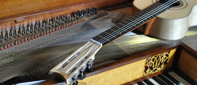 Gitarre liegt auf einem offenen Klavierflügel. 
