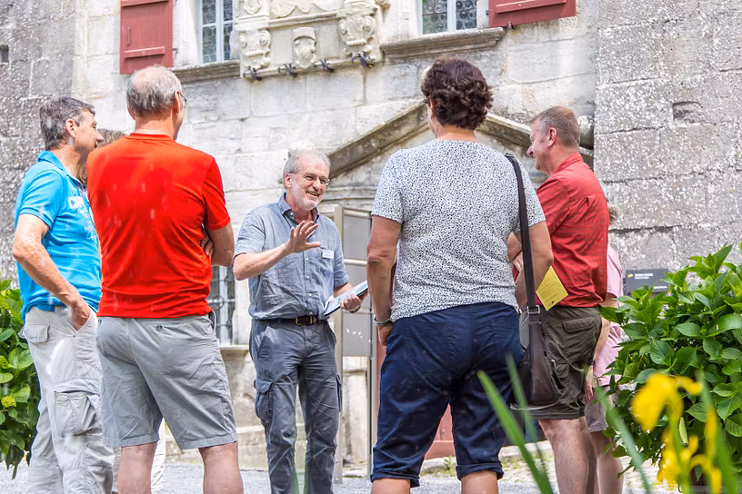 Ein Museumsführer steht mit Besucherinnen und Besuchern im Hof von Schloss Lenzburg. Er erklärt auf einer Führung spannendes zum Schloss.