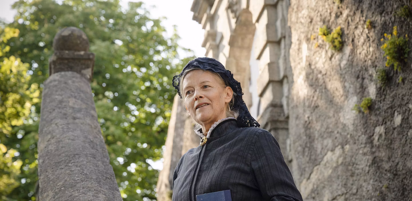 Eine Frau im Kostüm (als letzte Schlossherrin Julie von Effinger) steht auf einer Treppe im Aussenbereich von Schloss Wildegg