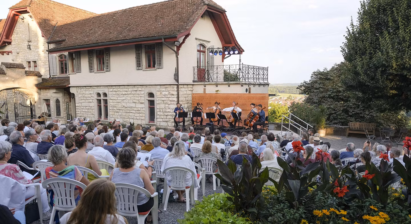 Hof von Schloss Wildegg mit Konzertbühne und vielen Besucherinnen und Besuchern.. Im Hintergrund die Villa von Schloss Wildegg.