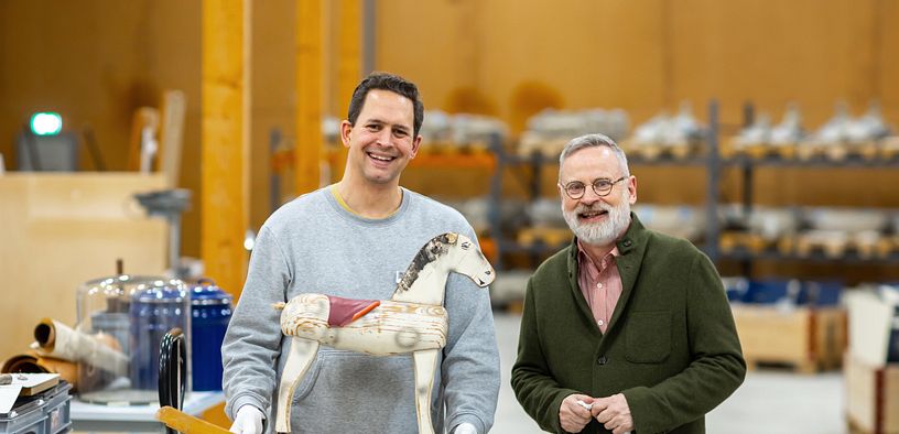 Zwei Männer im Sammlungszentrum Egliswil, der linke hält ein Schaukelpferd von Wisa-Gloria in den Händen.